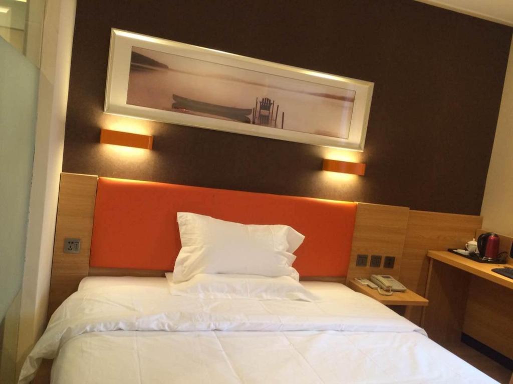 南京7天优品·南京新街口张府园地铁站店的一间卧室配有一张白色床和橙色床头板