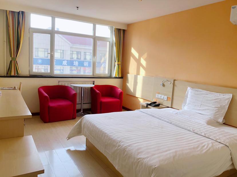 天津7天酒店·天津武清高铁站尚东金街店的酒店客房,配有一张床和两张红色椅子