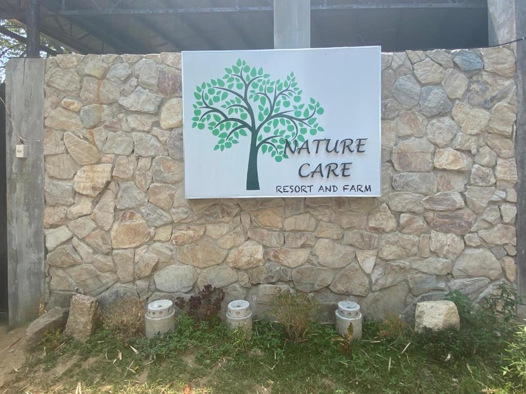 PulilanNature Care Resort and Farm的石墙上带有自然保护标志的标志