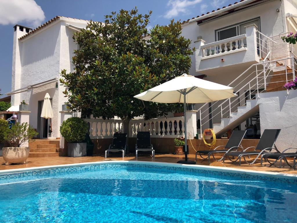 艾姆布里亚布拉瓦Casa Pani的房屋旁的游泳池配有椅子和遮阳伞