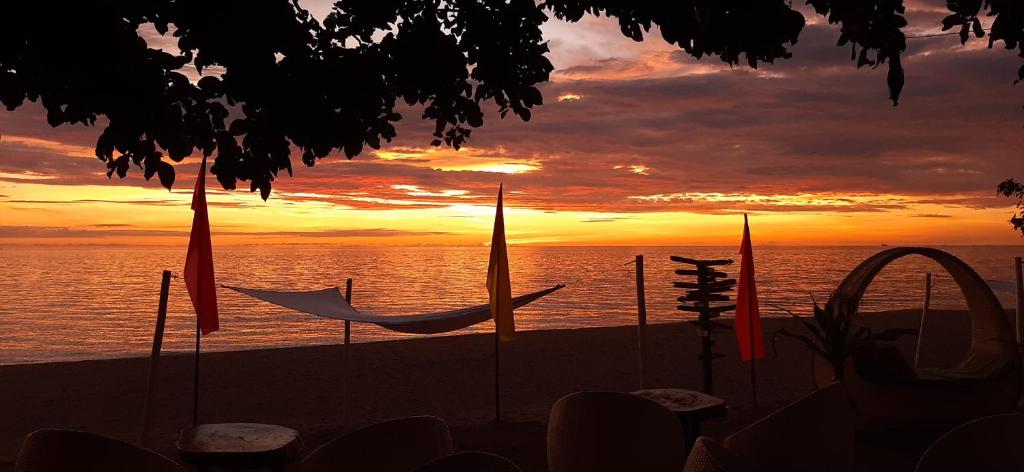 Hinoba-an布拉萨维尔海滩度假村 的海滩上带遮阳伞的海上日落