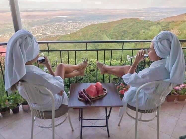 西格纳吉Zurabashvili Guest House的坐在椅子上,两个女人用餐桌的照片和食物