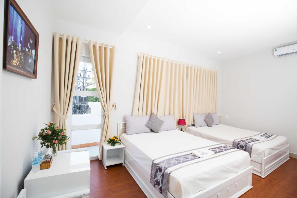 芽庄Nha Trang Pearl Hotel的白色客房的两张床,设有窗户