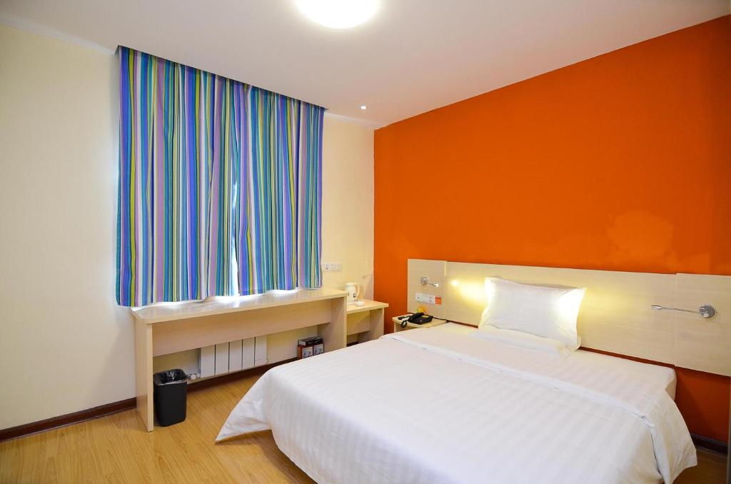 洛阳7天酒店·洛阳丽景门景区十字街店的卧室配有白色的床和橙色的墙壁