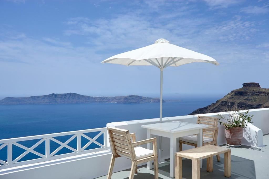 菲罗斯特法尼马诺斯微观世界酒店的阳台上配有白色的桌椅和遮阳伞
