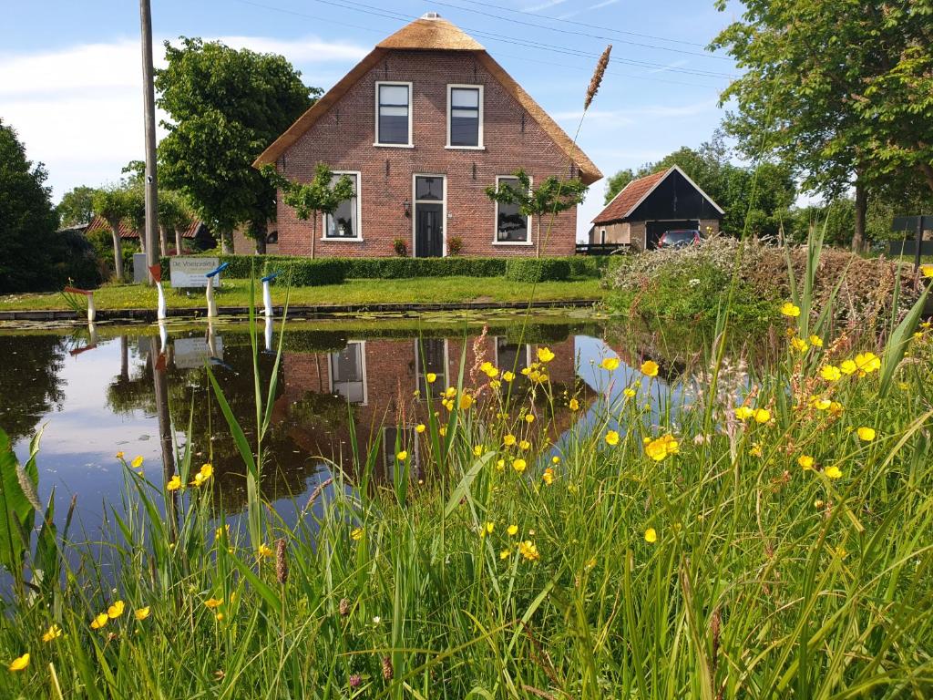 ReeuwijkHet Stalhuys的一座房子和一个前面有黄色花的池塘