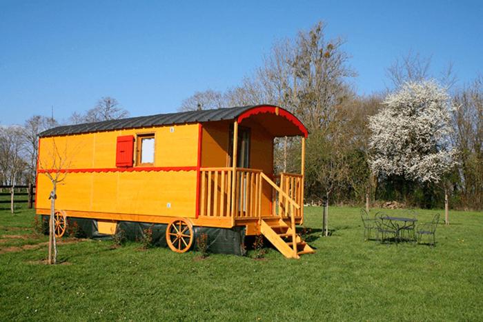 莫尔塔涅欧佩什Roulotte Poulette的坐在田野里的一辆黄色和红色火车车