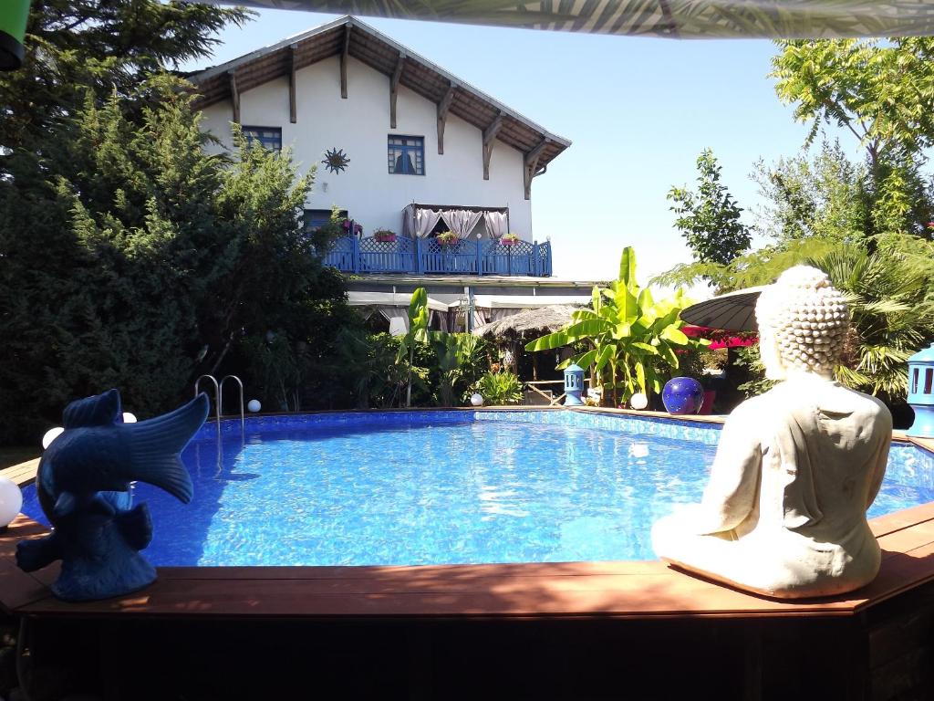 Souvans蓝色豪宅尚布尔酒店 的一座游泳池,两座雕像坐在房子旁边