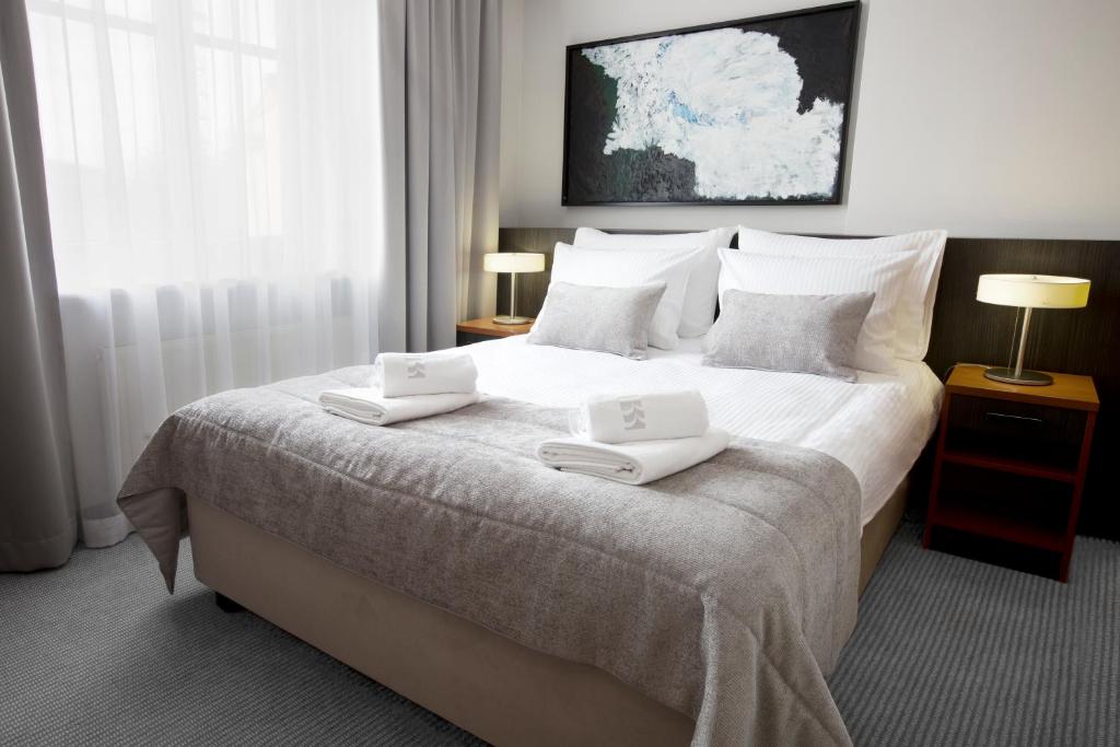 克拉科夫本尼菲斯精品酒店的一间卧室配有一张大床,上面有两条白色毛巾