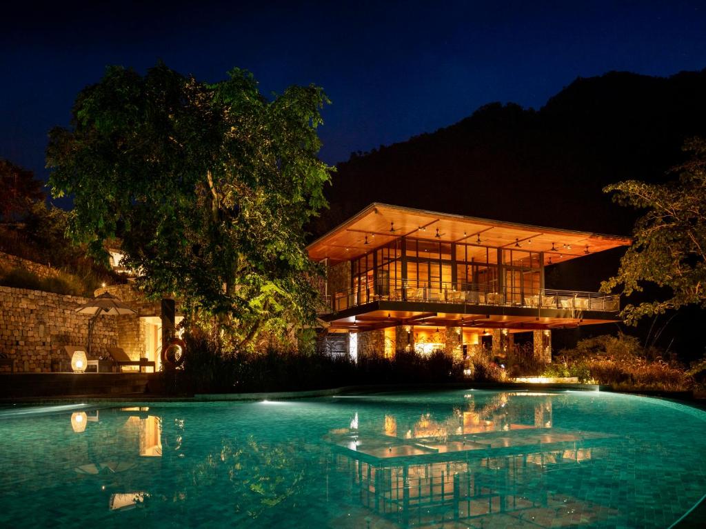 瑞诗凯诗Taj Rishikesh Resort & Spa Uttarakhand的一座晚上设有游泳池的房子