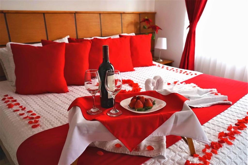 波哥大Hotel Embajada Real的红白的床铺,有果盘和酒杯