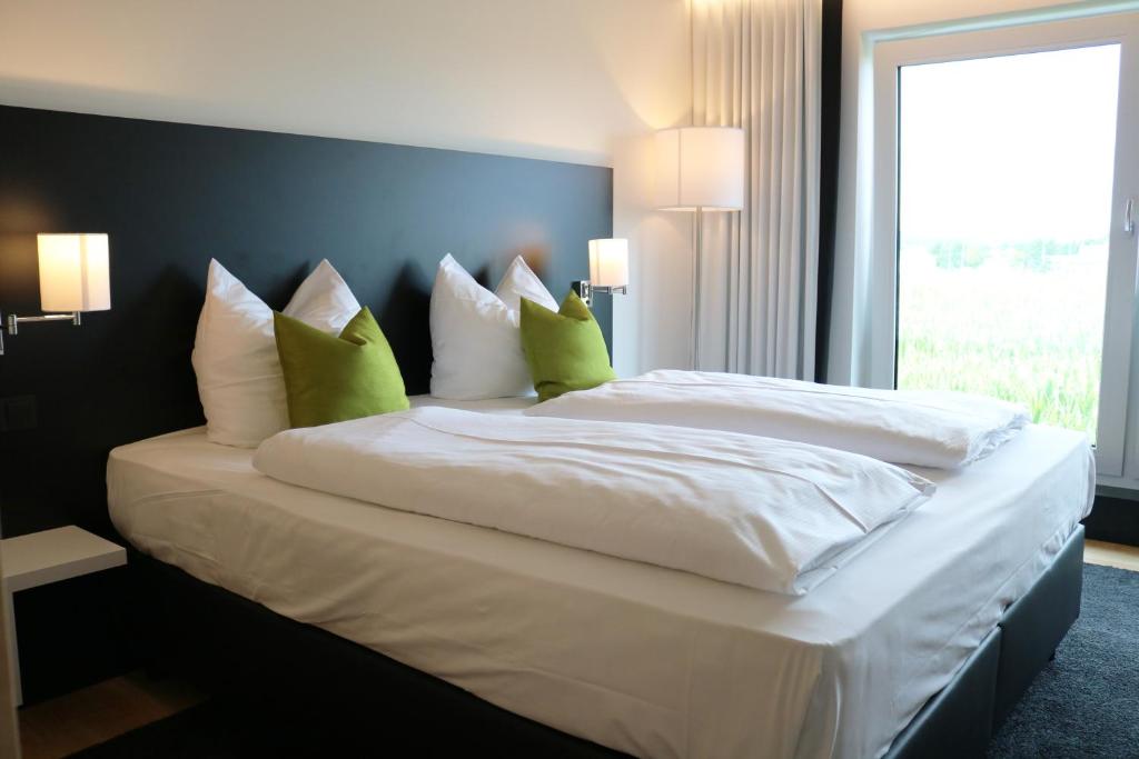 伊勒蒂森ILL Hotel by WMM Hotels的一张配有白色床单和绿色枕头的大床