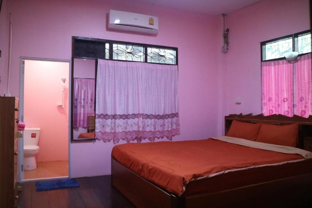 桑卡武里Baanmakpoo บ้านหมากพลู的一间卧室配有一张粉红色的墙壁和窗户。