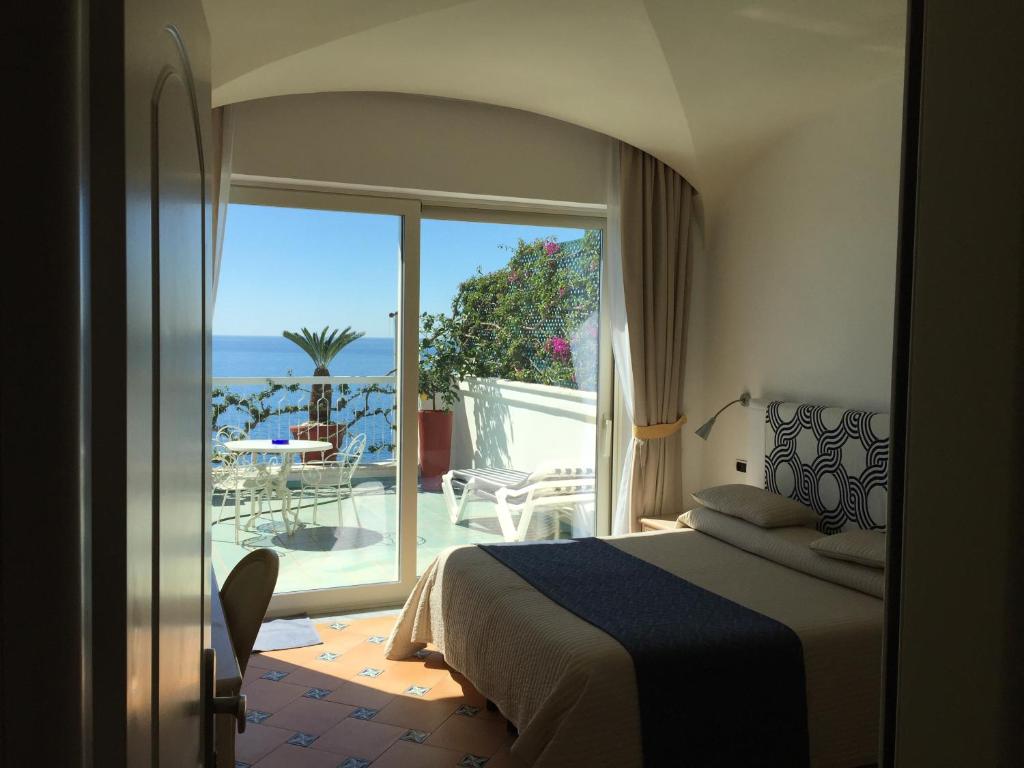 阿马尔菲贝尔维尤套房酒店的一间卧室配有一张床,享有海景