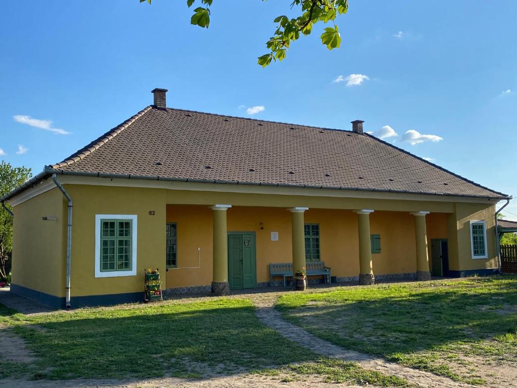 SzécsényHengermalom Kúria的一座黄色的小房子,设有绿门