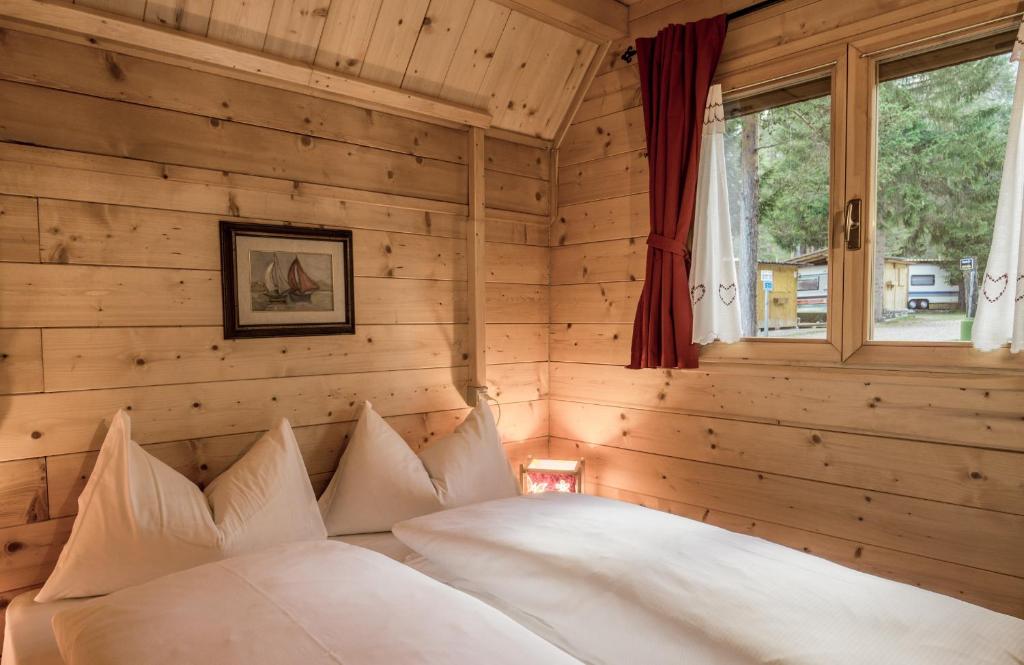 圣卡夏诺萨斯德拉西亚营地旅馆的卧室设有木墙和一张带白色枕头的床。