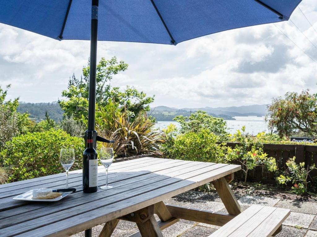 OpuaBlue Peter - Opua Holiday Home的一张带蓝伞和酒杯的野餐桌