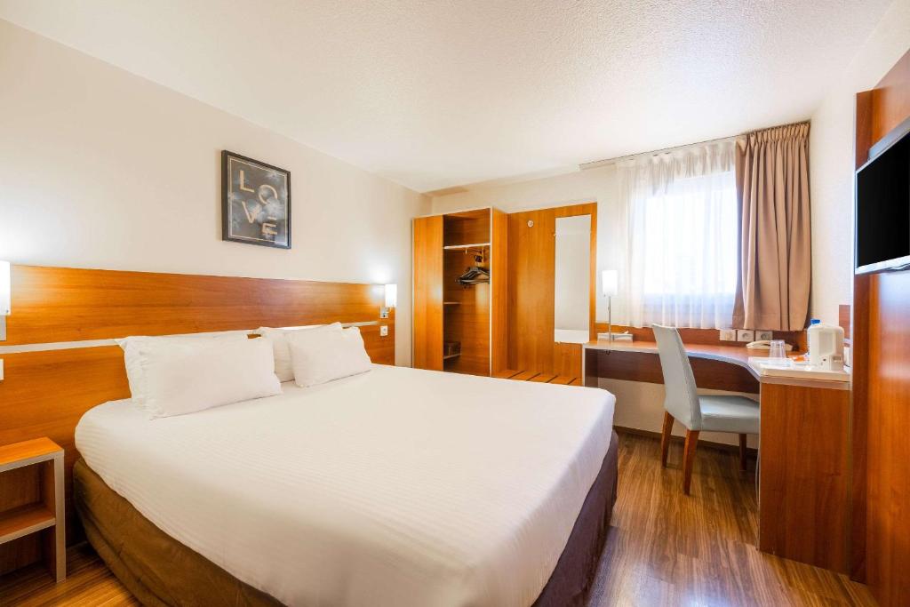 圣艾修伯里Comfort Hotel Aeroport Lyon St Exupery的酒店客房设有一张大床和一张书桌。