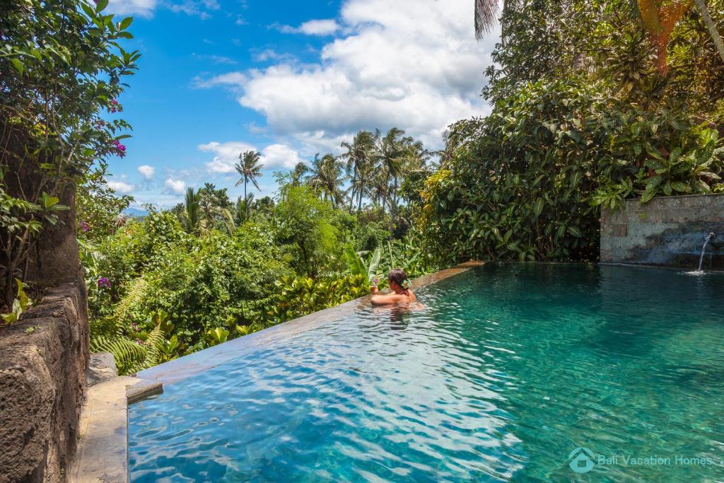 MayongTreasure of Bali, 3BR villa, infinity pool, staff的丛林中游泳池里的人