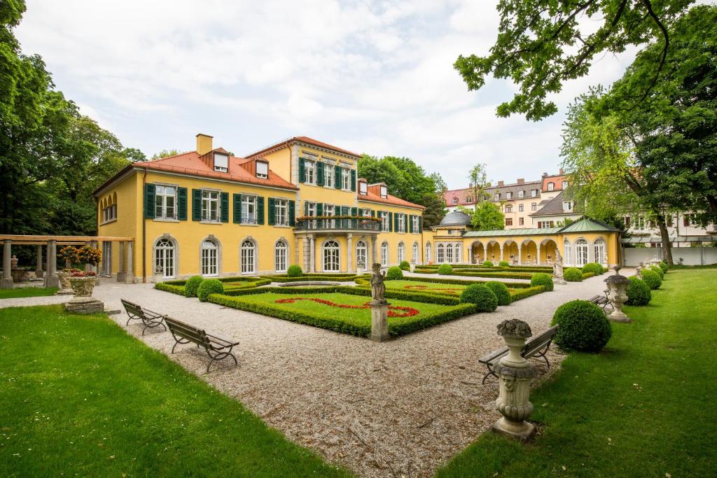 慕尼黑Gästehaus der Katholischen Akademie in Bayern的一座黄色的大房子,前面有一个花园
