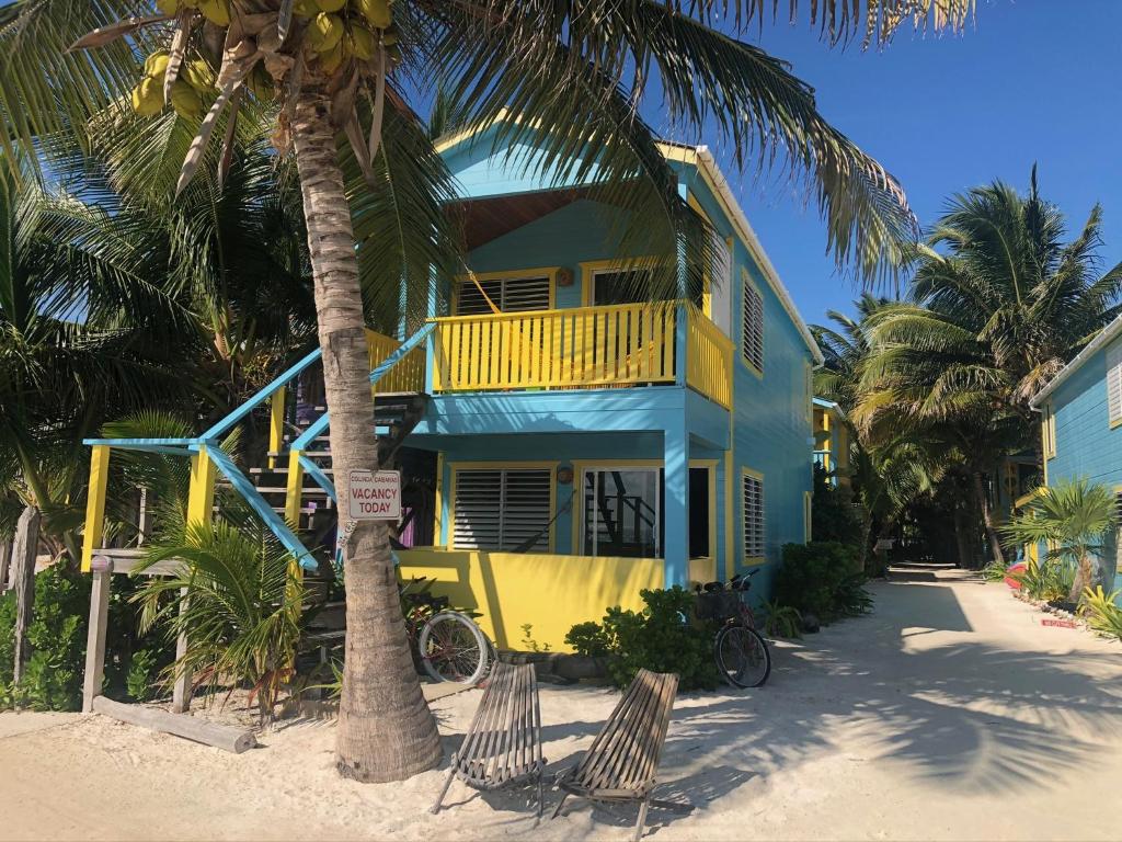 库尔克岛Colinda Cabanas的棕榈树海滩上的黄色和蓝色房子