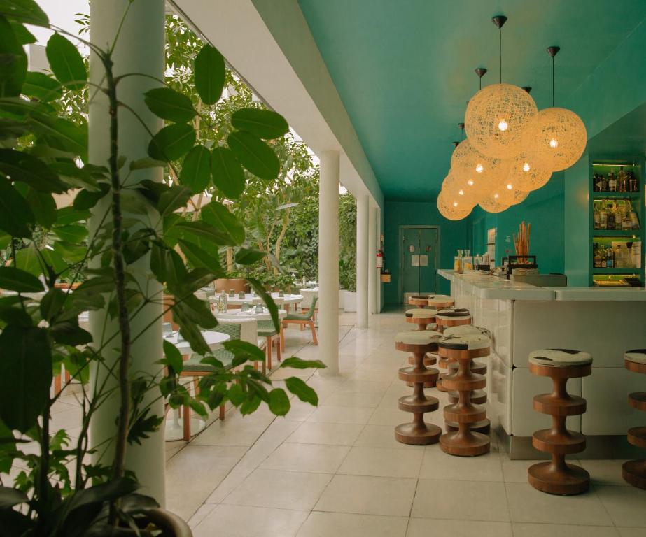 墨西哥城Condesa df, Mexico City, a Member of Design Hotels的一间拥有绿色墙壁的餐厅以及一个带凳子的酒吧