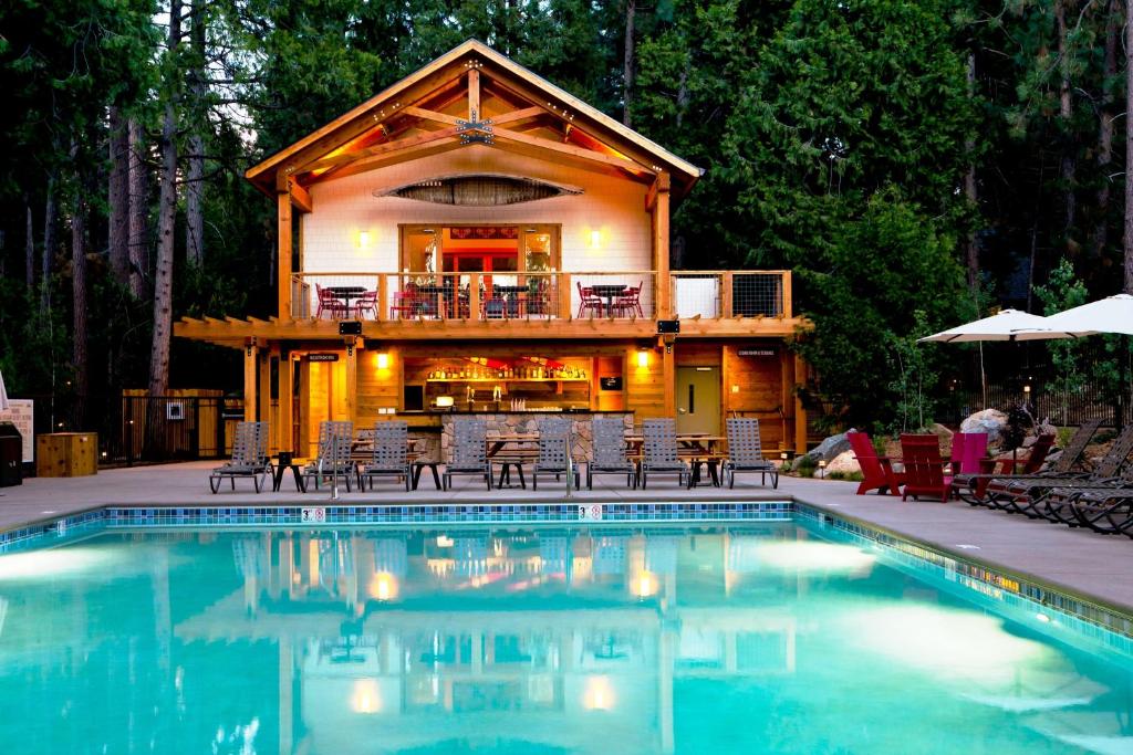 格罗夫兰优胜美地常青山林小屋的小木屋,房子前设有游泳池