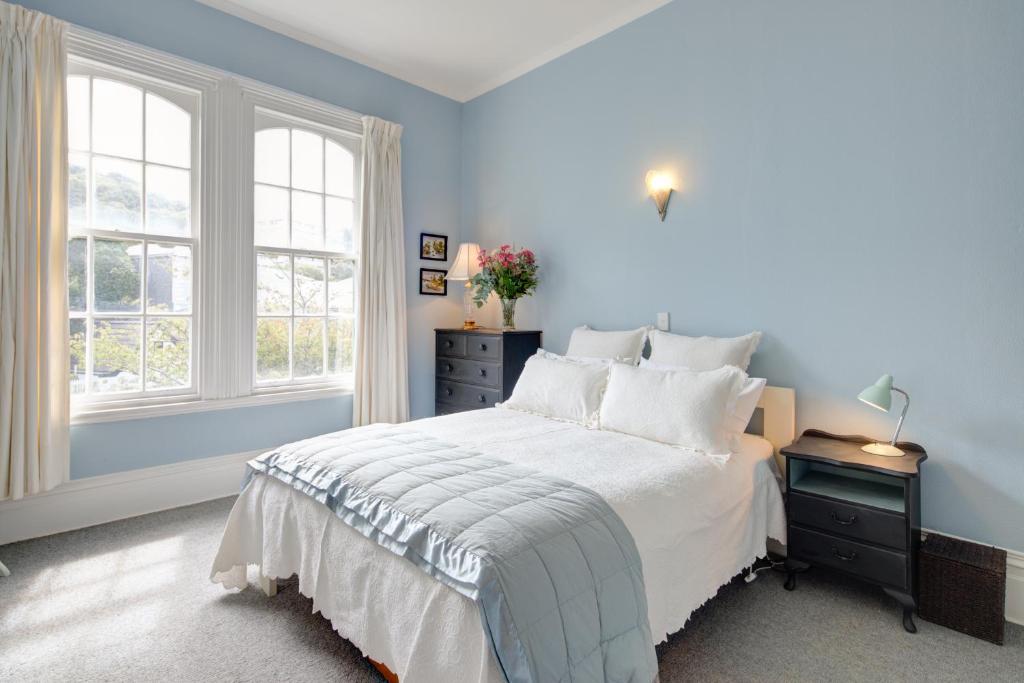 惠灵顿Thorndon Heritage Listed Villa的一间蓝色卧室,配有床和2个窗户