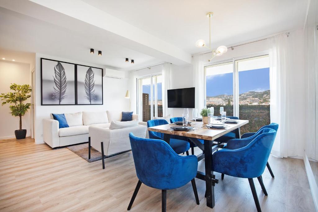 戛纳HeavnStay Suite Cannes Centre的客厅设有餐桌和蓝色椅子