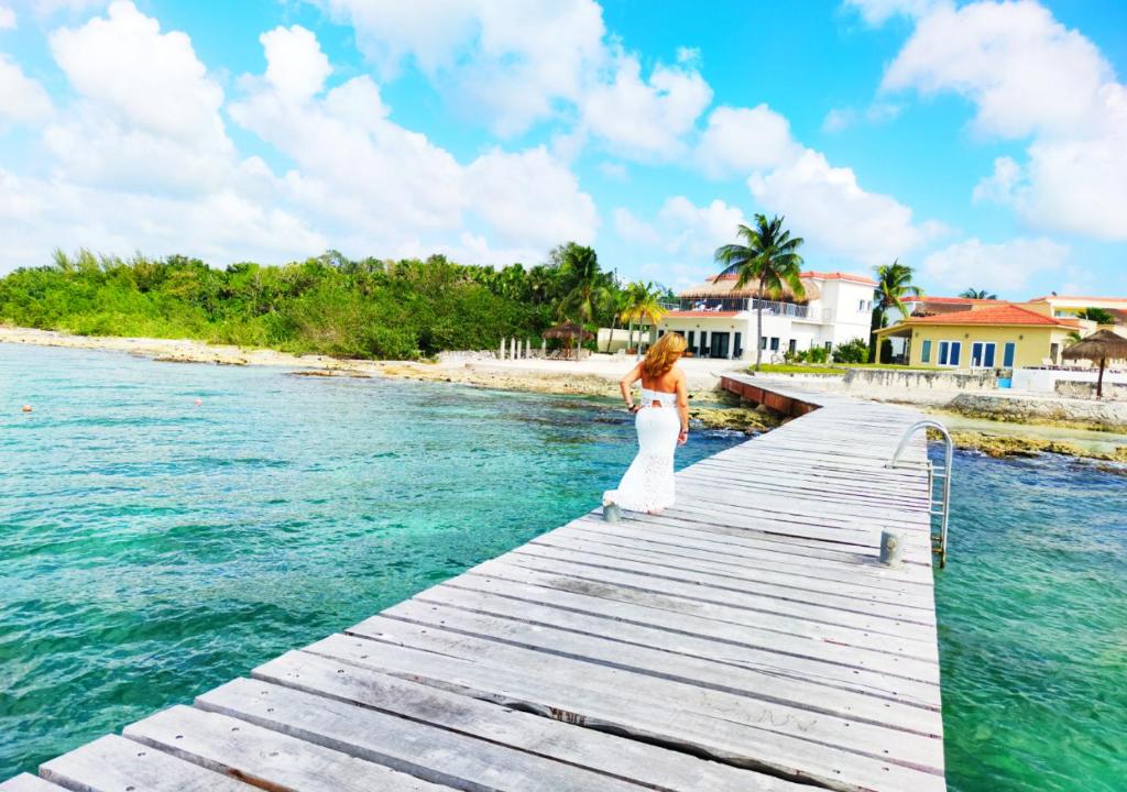 科苏梅尔The Queen of Cozumel Beach House -Luxury Beachfront Villa- MILLION DOLLARS VIEW的站在水面上的一个白色衣服上的女人