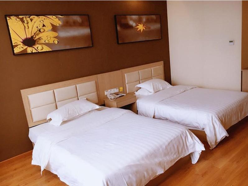 盐城7天酒店·盐城建湖秀夫南路店的配有白色床单的酒店客房内的两张床