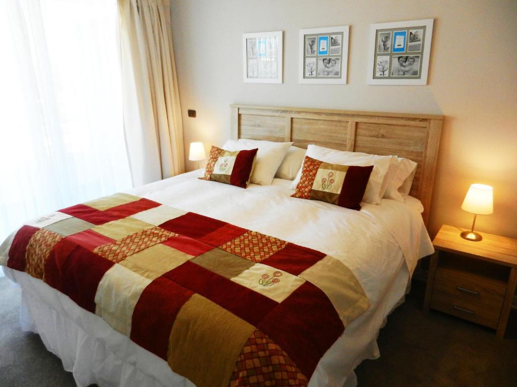 塔尔卡Apartamentos Terrazas de Talca的一间卧室配有一张大床和五颜六色的被子