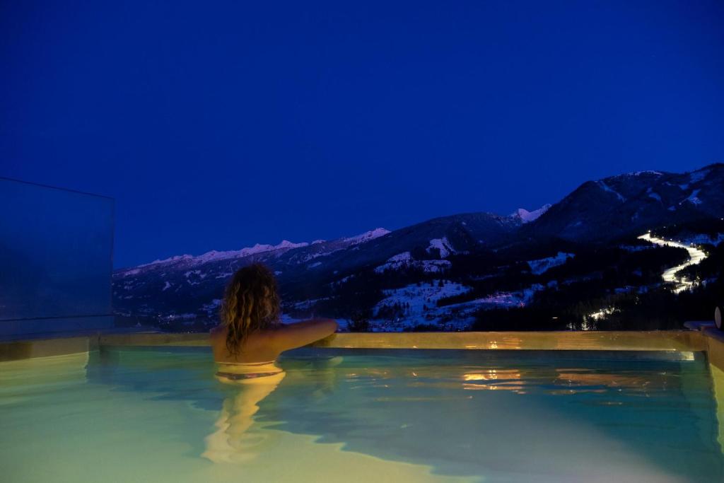 卡瓦莱塞La Roccia Wellness Hotel的一位坐在热水浴缸中的女人,看着群山