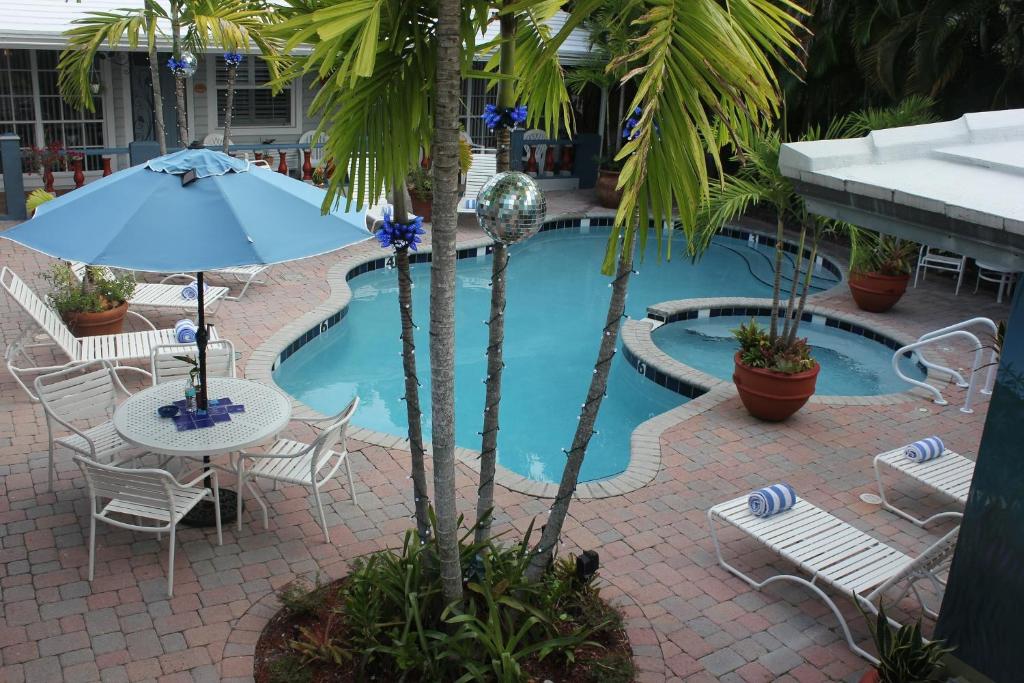 劳德代尔堡珊瑚礁宾馆的一个带椅子和桌子的游泳池以及一把遮阳伞