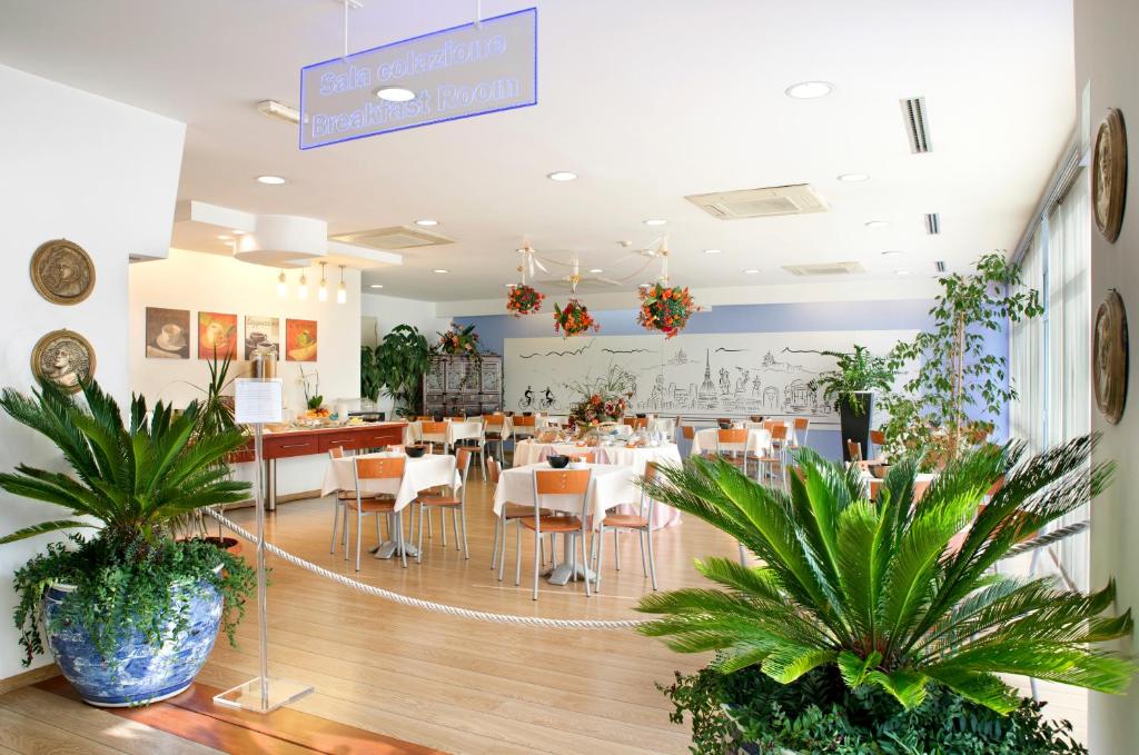 都灵马斯特酒店的一间设有桌椅的餐厅,种植了植物