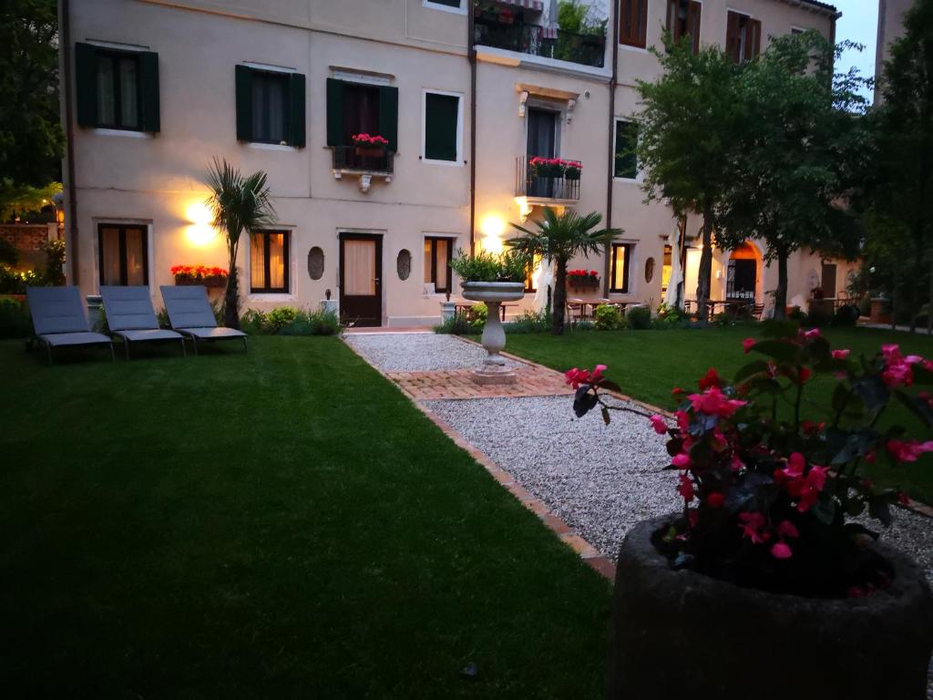 威尼斯Cinqueteste Luxury Home的一座带椅子的白色大建筑,在院子里