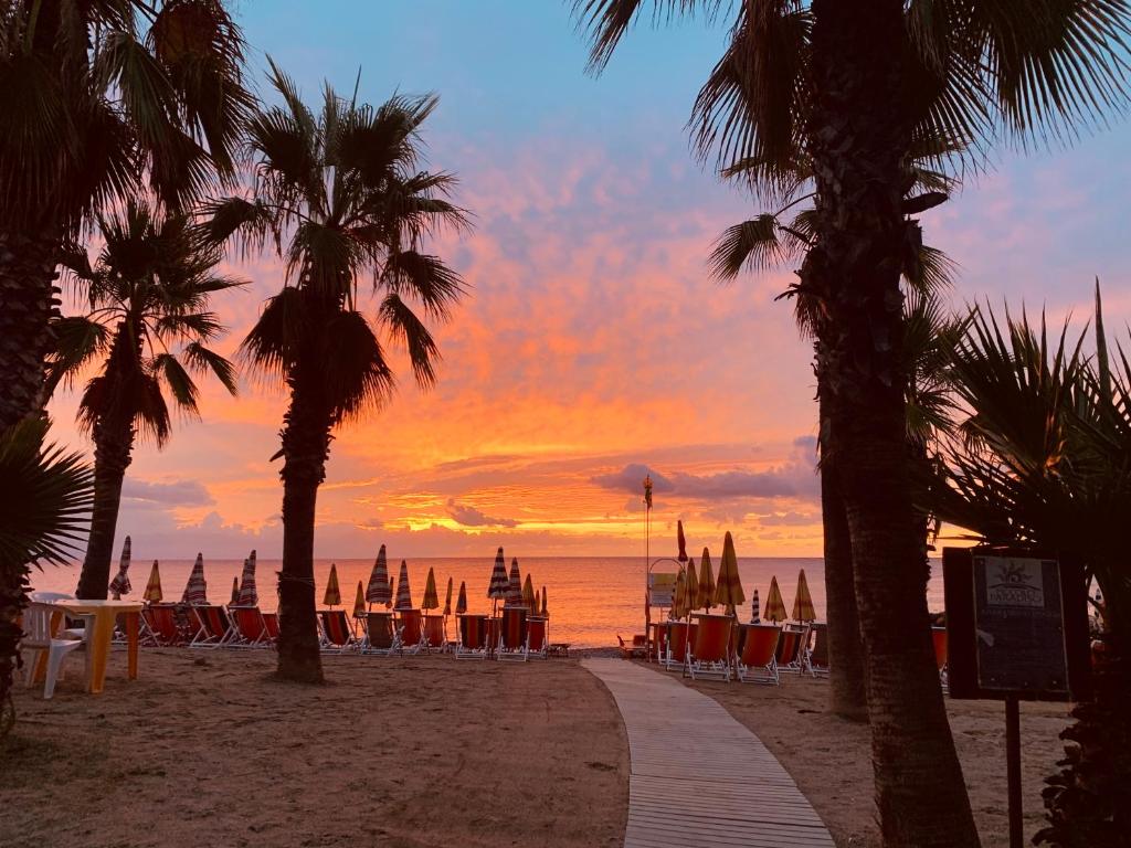 阿尔本加Piccolo Paradiso的海滩上的日落,配有椅子和遮阳伞