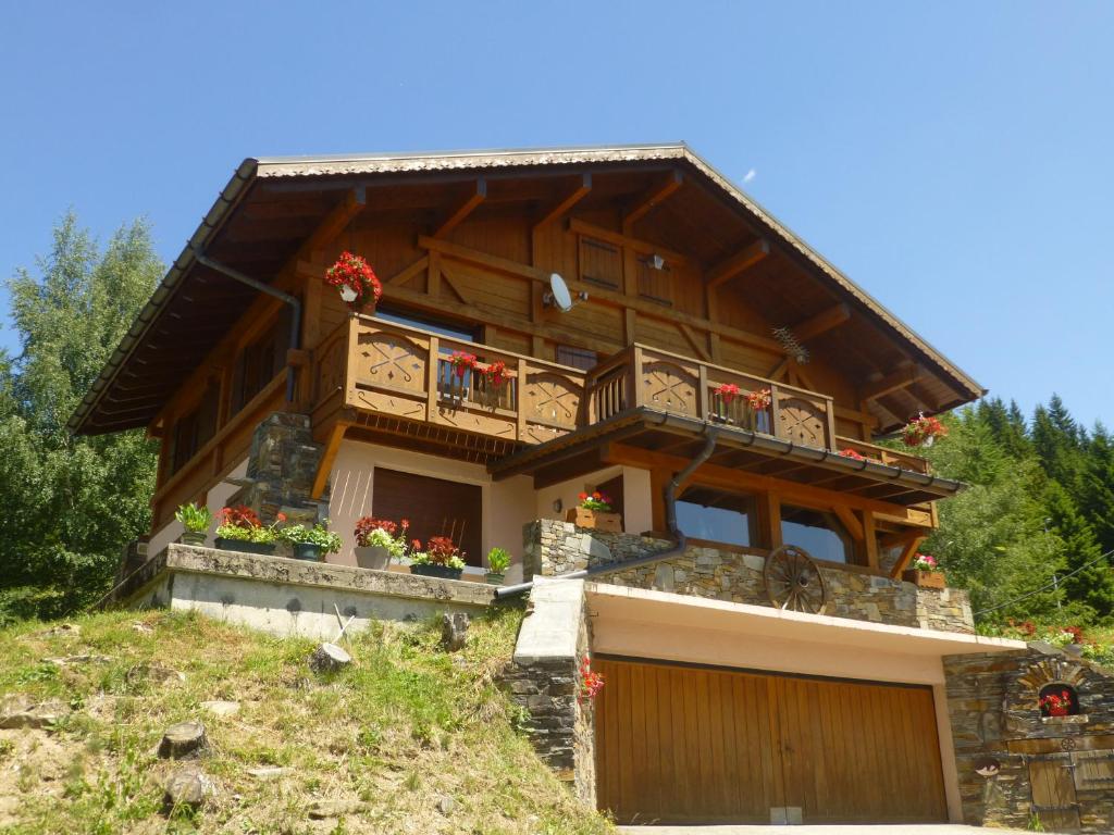 雷塞兹Les Saisies côté Bisanne appartement dans chalet LE Népal的阳台上鲜花盛开的小山上的房子