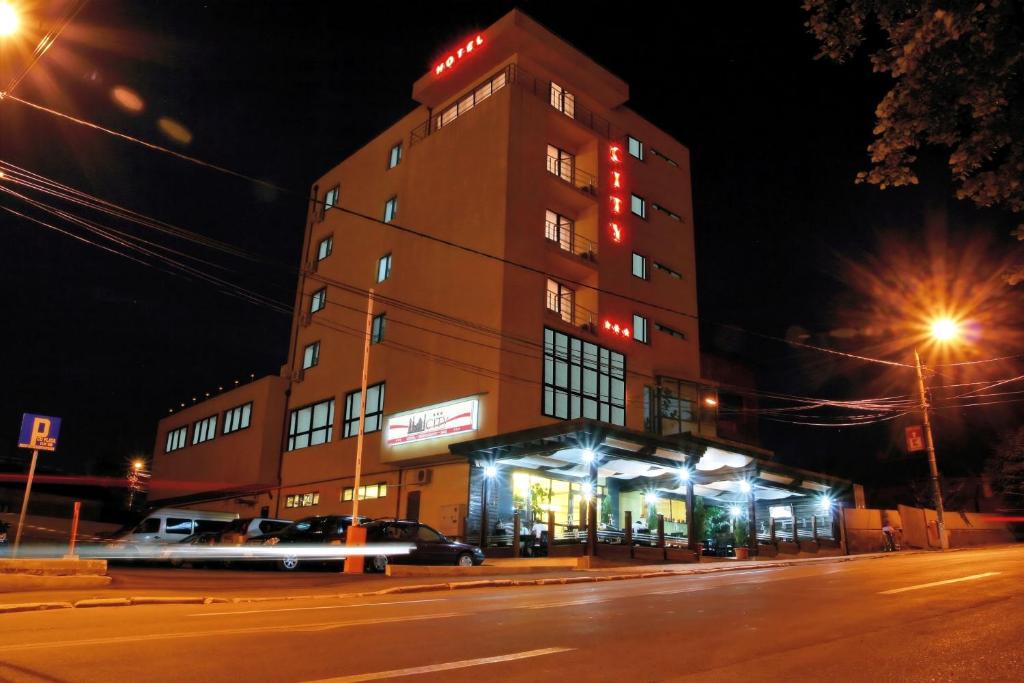 图尔恰城市酒店的街上的一座建筑物,晚上停在前面