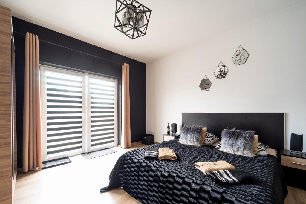 DębnoApartament Perła Pienin的一间卧室设有一张黑色的床和一个大窗户