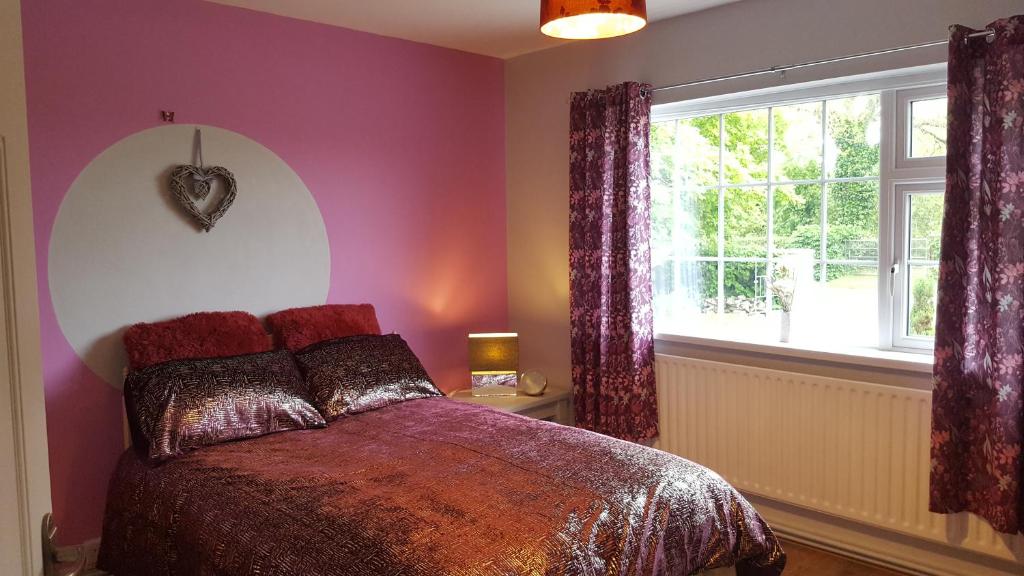 RochfortbridgePauleens Peaceful Place的一间卧室配有一张紫色墙壁和窗户的床