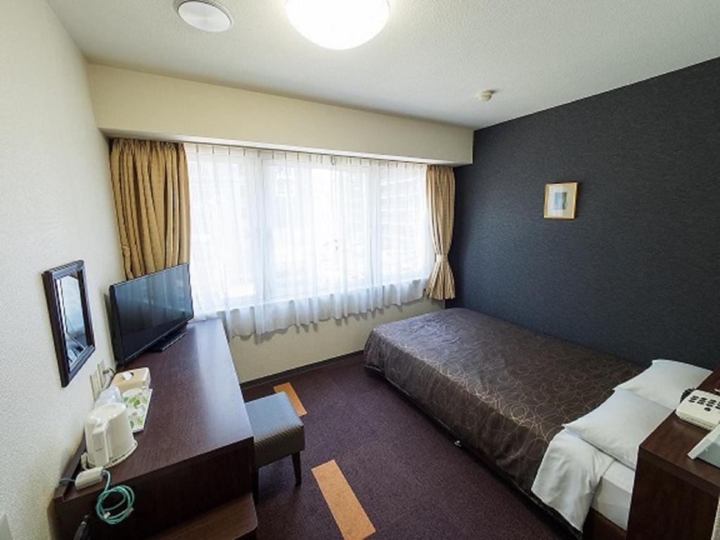 大阪Hotel Shin Osaka / Vacation STAY 81521的配有一张床、一张书桌和一扇窗户的酒店客房