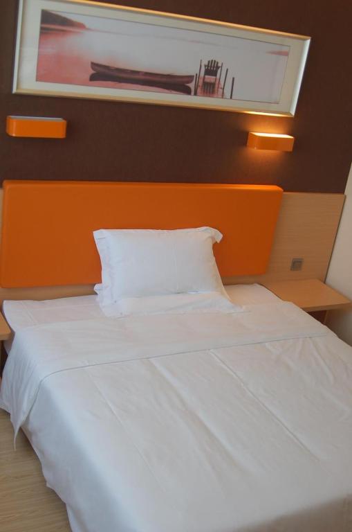 吴忠7天优品·吴忠万达广场店的一张大白色的床,在房间里装有橙色床头板