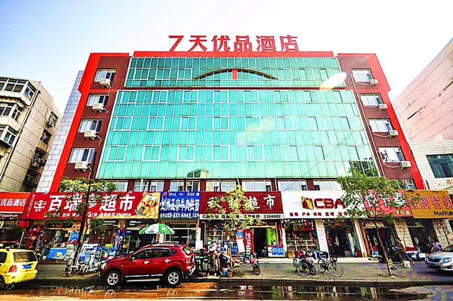 秦皇岛7天优品·秦皇岛河北大街四道桥店的城市里一座建筑物,前面有车辆停放