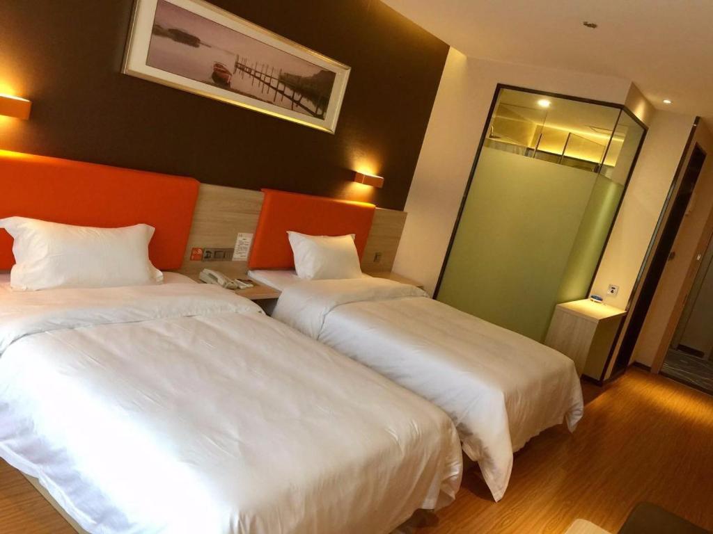 大足7天优品·重庆大足石刻新城店的酒店客房,设有两张床和镜子
