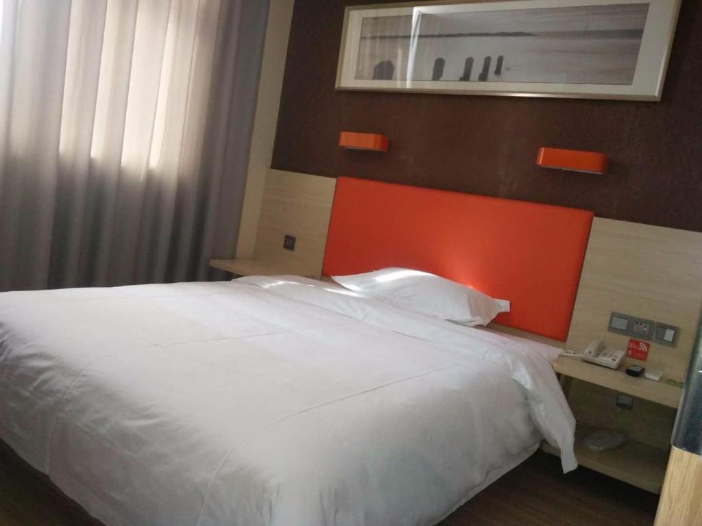 定西7天优品·定西火车站店的一间卧室配有一张白色床和橙色床头板
