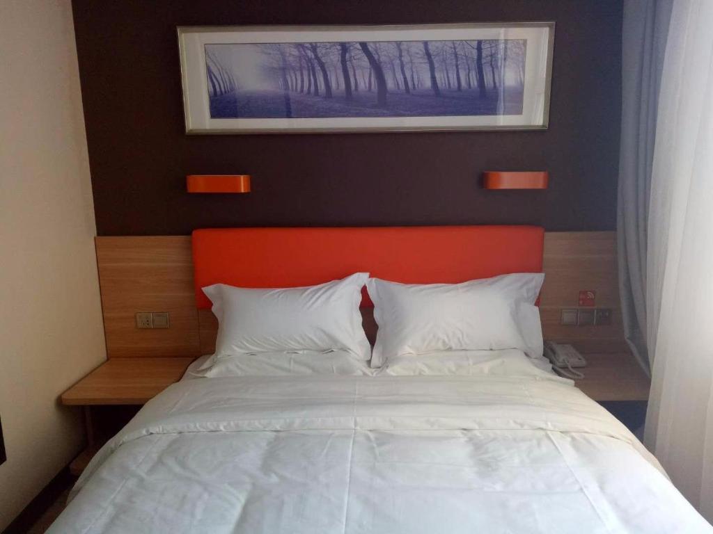 Nenjiang7天优品·黑河嫩江县客运站店的一张带橙色床头板和白色枕头的床