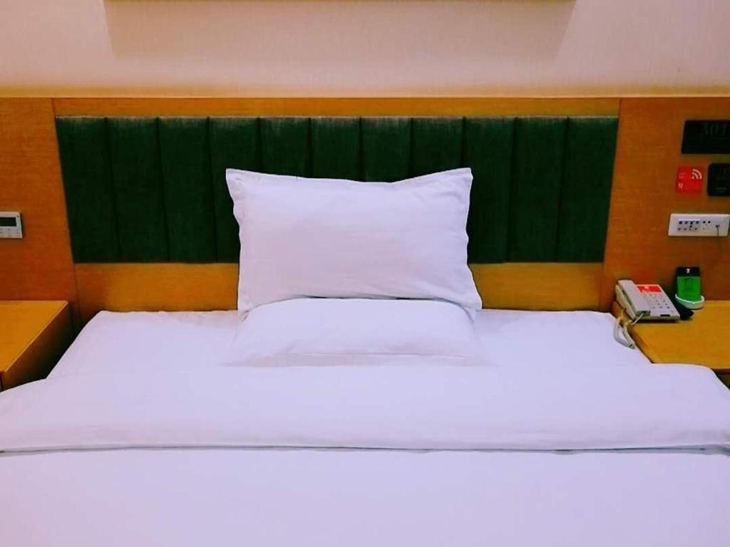 十堰7天优品十堰人民路三堰客运站店的一间卧室配有一张白色大床和绿色床头板