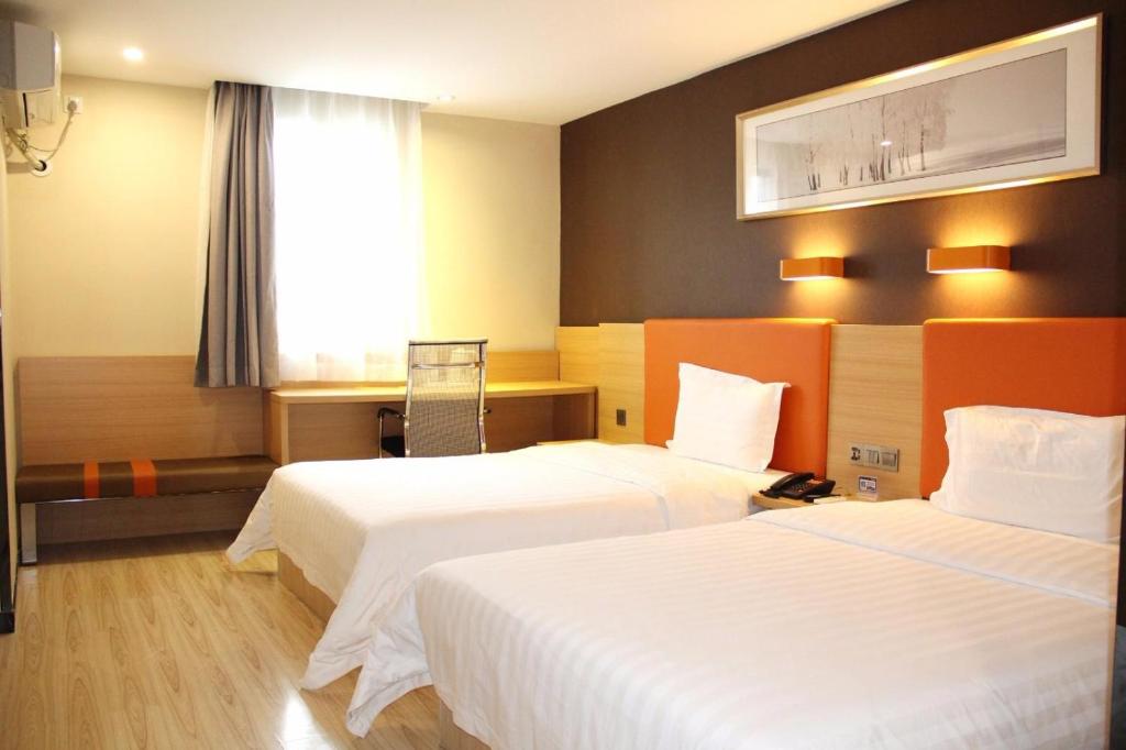海口7天优品·海口明珠广场五指山路店的酒店客房设有两张床和窗户。
