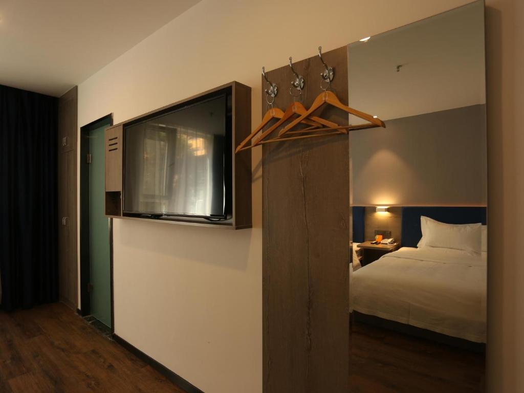 西宁7天优品·西宁大什字中心店的卧室配有一张床,墙上配有电视。